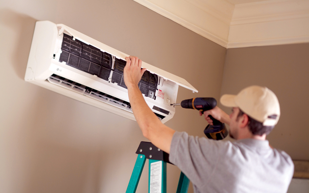 Technician installing an indoor ductless mini-split wall unit in a Dallas home