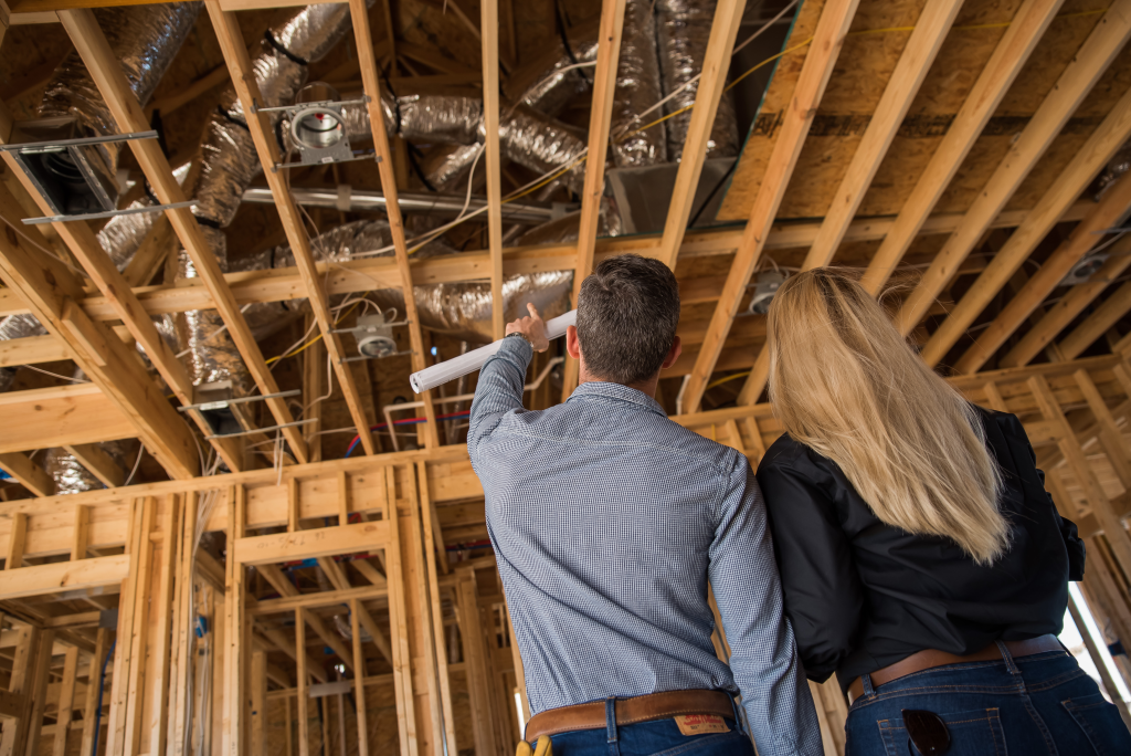 Couple reviewing ductwork installed in the ceiling framing of a new construction home in Dallas